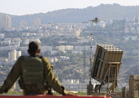 An Israeli soldier is seen next to an Iron Dome rocket interceptor battery / AP