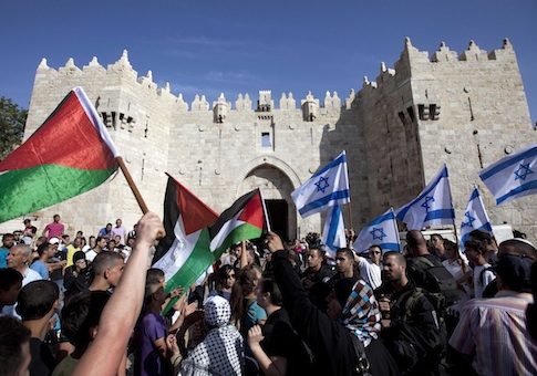 Israelis and Palestinians wave flags as Israelis march celebrating Jerusalem Day outside Damascus Gate in Jerusalem's old city