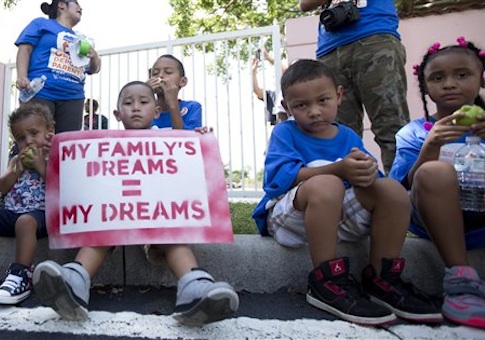 Kids sit on the sidewalk during an immigration rally in Deerfield Beach, Fla., Wednesday, Aug. 14, 2014