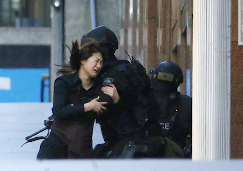 A hostage runs towards a police officer outside Lindt cafe, where other hostages are being held, in Martin Place in central Sydney December 15, 2014