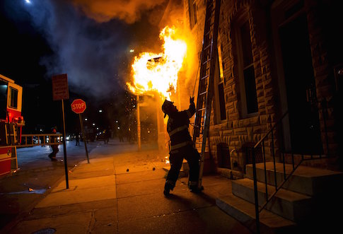 A Baltimore firefighter attacks a fire in a convenience store and residence
