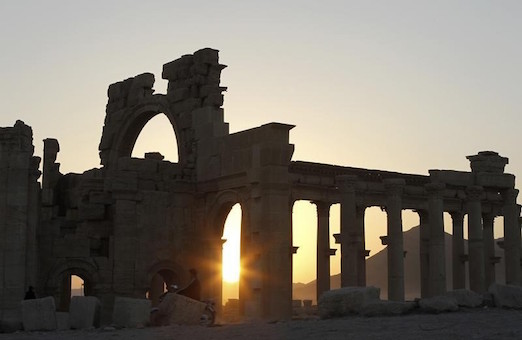 The sun sets behind ruined columns at the historical city of Palmyra, in the Syrian desert
