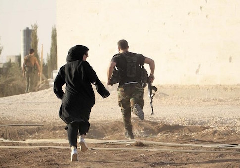 A woman reporter runs with a rebel fighter to avoid snipers at the frontline against the Islamic State fighters in Aleppo's northern countryside