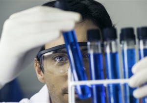 Researcher scrutinizing test tubes in laboratory (PhotoAlto via AP Images)