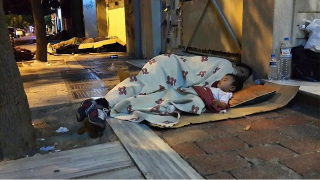 One week earlier Roxanna sleeps on cardboard bedding on an Athens sidewalk.