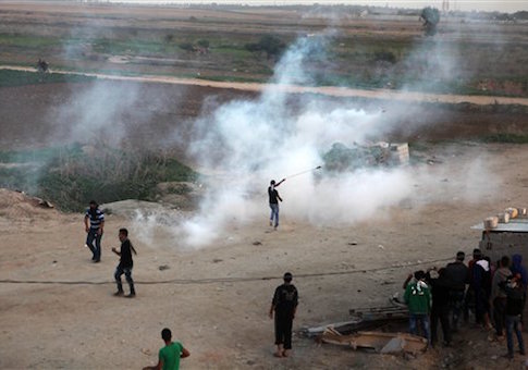 Palestinian protesters throw back tear gas canister that was fired towards them by Israeli soldiers during clashes, as seen from the Israeli side of the border fence with central Gaza / AP