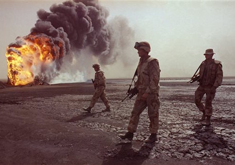 A U.S. Marine patrol walks across the charred oil landscape near a burning well during perimeter security patrol near Kuwait City in 1991