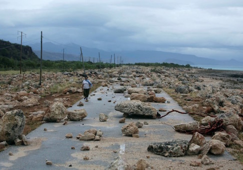 A woman walks on a highway blocked by rocks after the passage of hurricane Matthew on the coast of Guantanamo province