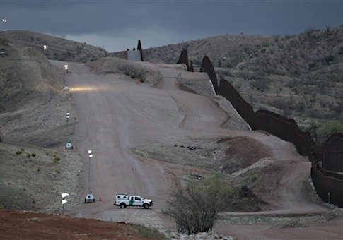 A Customs and Border Patrol agent patrols along the international border after sunset in Nogales, Ariz. / AP
