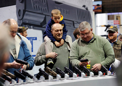 Visitors view a gun display at a National Rifle Association outdoor sports trade