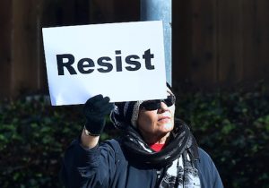 A woman holds a placard reading 'Resist'