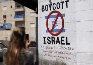 A tourist photographs a sign painted on a wall in the West Bank biblical town of Bethlehem