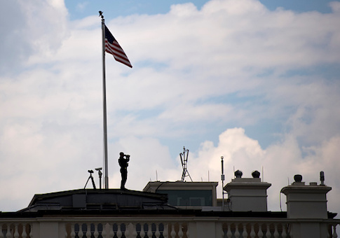 A secret service officer stands atop the White House in Washington, DC, April 21, 2017