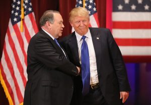 Republican presidential candidate Donald Trump (R) and rival candidate Mike Huckabee shake hands during the rally for veterans at Drake University on January 28, 2016 in Des Moines, Iowa. / Getty Images