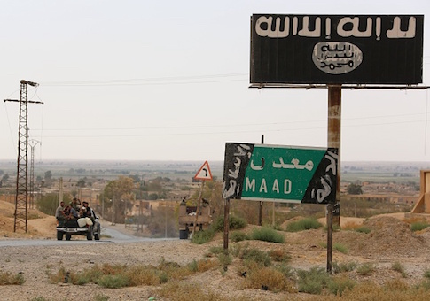A vehicle drives past a billboard bearing the logo of the Islamic State group in Madan area, in the countryside of Deir Ezzor