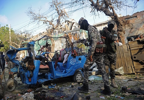 Somali soldiers stand near damaged vehicles after a car bomb for which al-Shabaab took responsibility