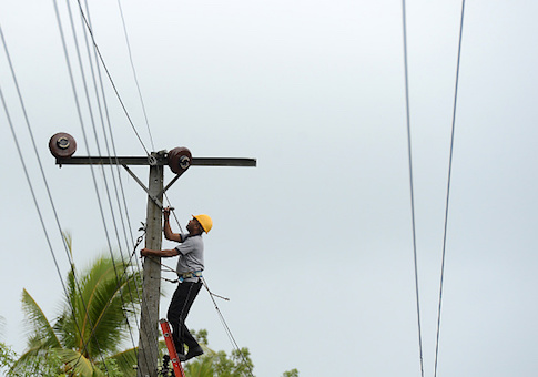 A worker is seen on top of an utility pole